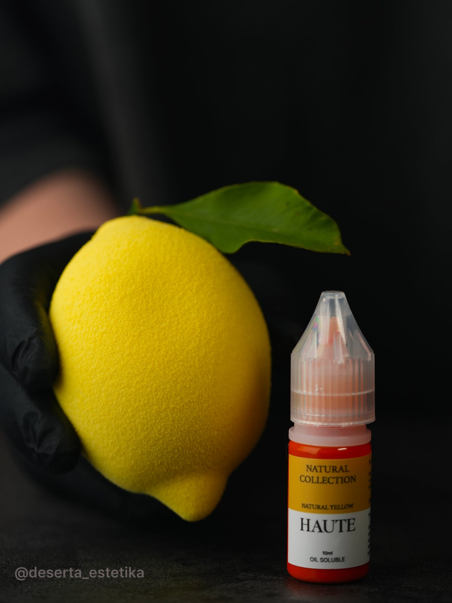 Yellow lemon held by a gloved hand next to a bottle labeled 'HAUTE'. Best Natural Haute Food Colors by Ksenia Penkina, Vegetable Colours, Liquid Gel, Water Soluble, Oil Soluble, Fat Soluble Gel, Food Colouring, Chefrubber, Colourmill, Chefmaster, Silikomart, Pavoni, Decorelief, Matfer, PastryClass, Valrhona, Cacao Barry, For Macarons, For Glazing